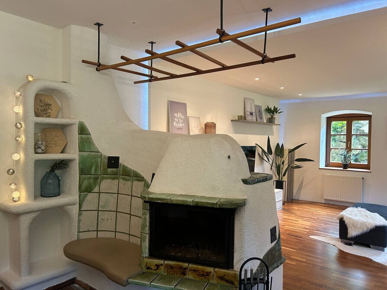 Un salon moderne doté d’une cheminée, de poutres en bois, d’un escalier et d’une fenêtre offrant une vue agréable.