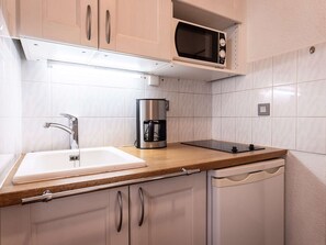 Eine moderne Küche mit Spüle, Kaffeemaschine, Mikrowelle und Geschirrspüler.