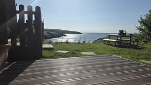 A deck with a view of the ocean, a picnic table, and a wooden gate. - Two Pod Glamping Retreat in Kinsale, Sea Views (Kinsale)