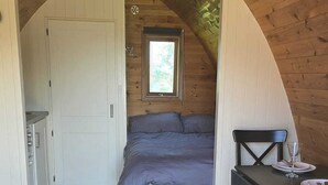A bedroom with a bed, a small table with a chair, a window, and a door. - Two Pod Glamping Retreat in Kinsale, Sea Views (Kinsale)