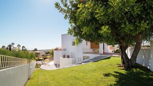 Un bâtiment moderne de couleur blanche, doté d’un escalier, d’un arbre et offrant une vue sur les environs.