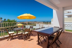 Ein Balkon mit Tisch, Stühlen und einem gelben Sonnenschirm.