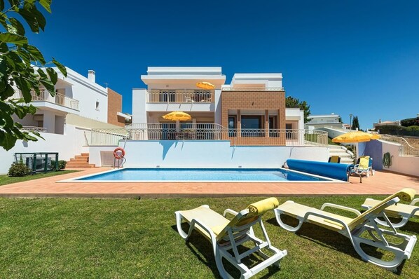 Ein Pool mit Liegestühlen, einem Rettungsring und Sonnenschirmen.