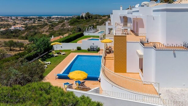 Un bâtiment moderne doté d’une piscine sur le toit, d’un espace extérieur aménagé et offrant une vue sur la mer.