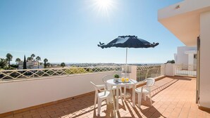 Une terrasse avec une table, des chaises et un parasol, d’où l’on a une vue sur le paysage urbain.