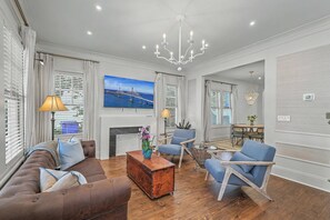 Ein modernes Wohnzimmer mit einer Couch, Sesseln, einem Couchtisch und einer Deckenleuchte.