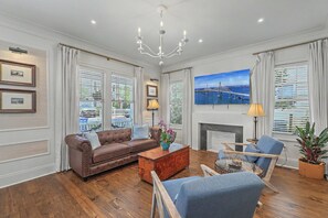 Ein Wohnzimmer mit braunem Ledersofa, einem Holztisch, einem blauen Sessel und einem Kamin.