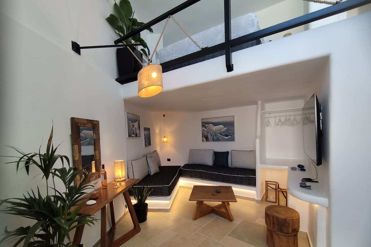 Una sala de estar moderna con sofá, una mesa de centro, televisor y un comedor con mesa y sillas de madera.