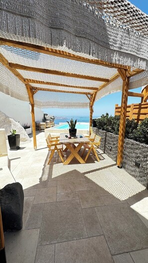 A covered outdoor seating area with a view of the sea.