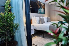 Ein Schlafzimmer mit einem Bett, einem Nachttisch, einer Zimmerpflanze und einem Bild an der Wand.