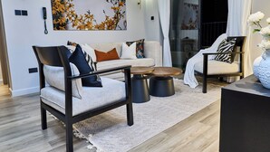 A modern living room with a sofa, armchair, coffee table, and decorative pillows. - Novelle By Edmor Suites (Nairobi)