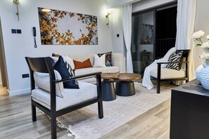 Ein modernes Wohnzimmer mit Sofa, Sessel, Couchtisch und dekorativen Kissen.