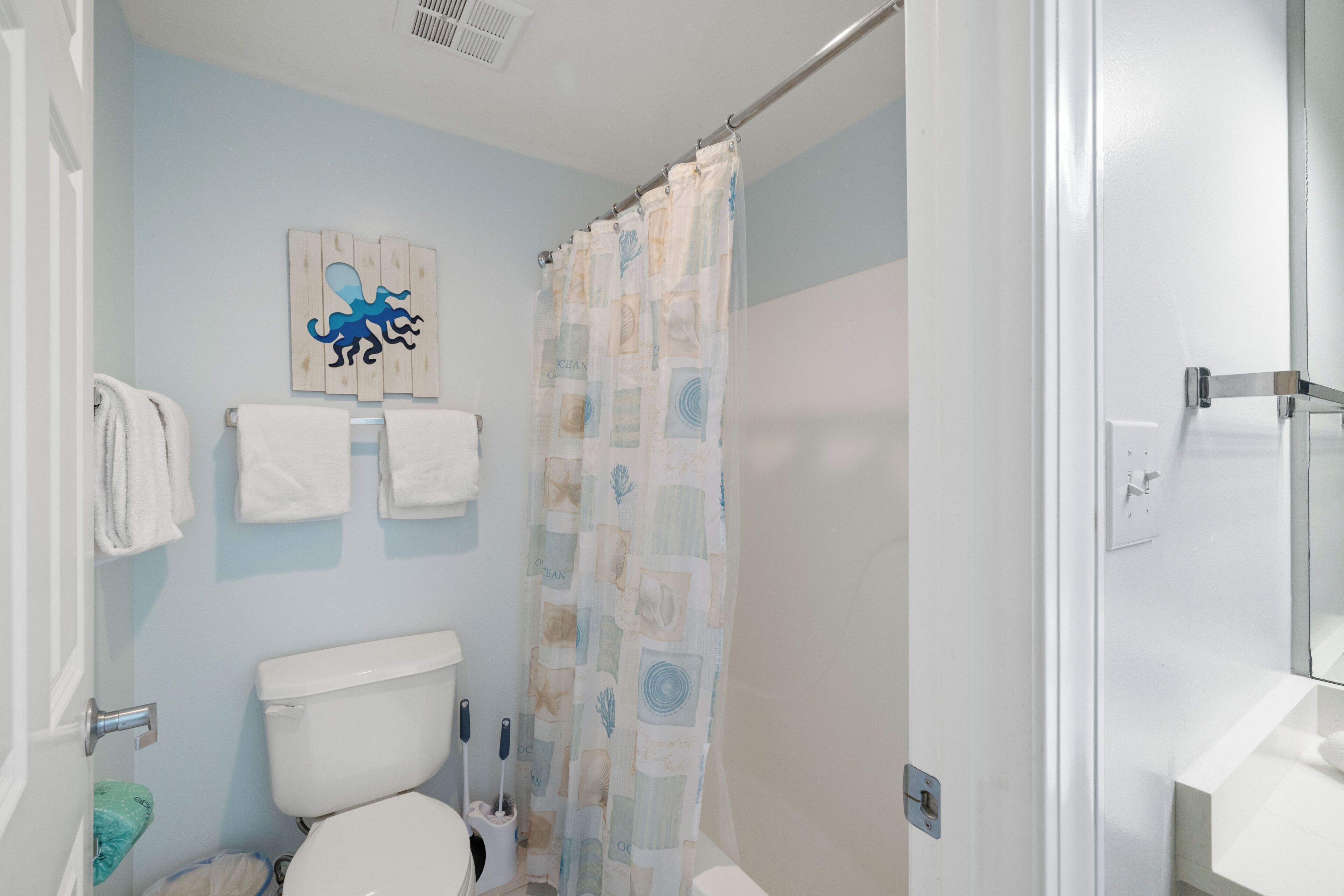 A bathroom with a toilet, a shower curtain, and a wall-mounted towel rack with towels.