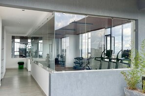 Ein modernes Fitnessstudio mit Trainingsgeräten, großen Fenstern und einer Glaswand.