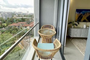 Ein Balkon mit Korbstühlen und Blick auf eine Stadtlandschaft.