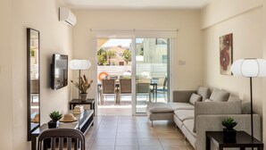 A modern living room with a sofa, a dining table, and a TV. - Protaras Seaside Villa Andria (Paralimni)