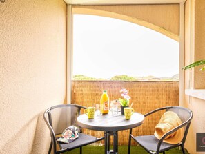 A balcony with a table set for two, featuring a bottle of orange juice, a glass, and a potted plant. - Cozy apartment - 4 guests, heart of Biscarrosse Beach (Biscarrosse)