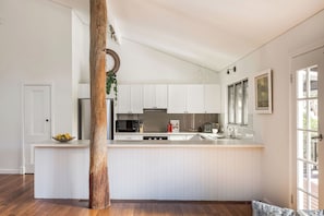 A kitchen with white cabinetry, a wooden pillar, and a bowl of fruit on the counter. - PEACEFUL AND SERENE RURAL COTTAGE SITUATED IN QUINDALUP ON 4.5 ACRES (Quindalup)