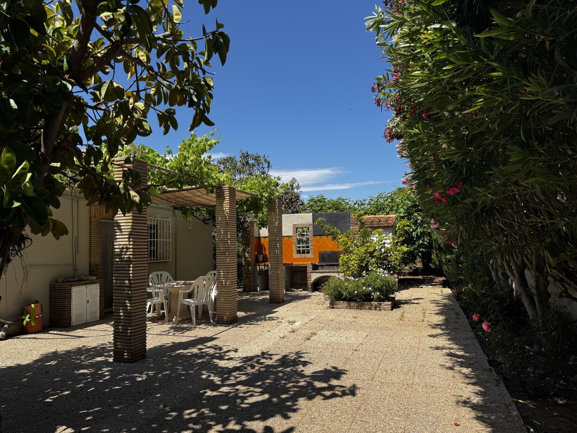 Ein Innenhof mit Sitzgelegenheit, einem kleinen Gebäude und einem Garten.