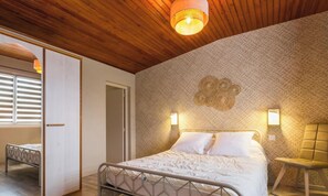 A bedroom with a bed, a wooden ceiling, and a patterned wall.