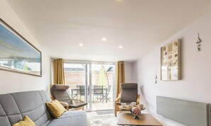 A modern living room with a grey sofa, a coffee table, and a dining area with chairs and a table.