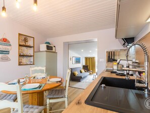 A compact kitchen with a sink, a microwave, and a dining area with a table and chairs.