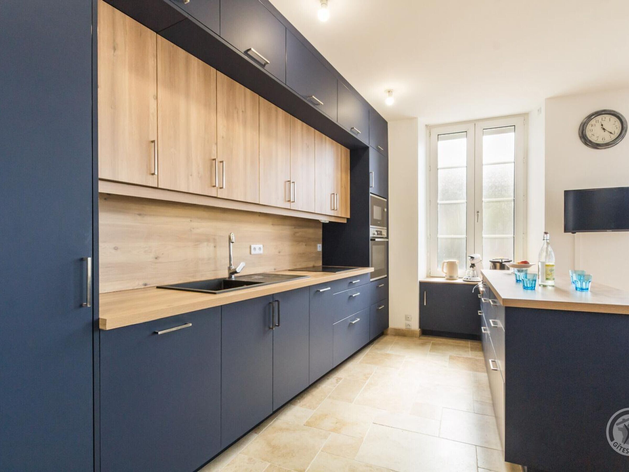 A modern kitchen with dark cabinets, a wooden countertop, and a built-in oven.