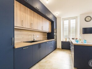 Eine moderne Küche mit dunklen Schränken, einer Holz Arbeitsplatte und einem eingebauten Backofen.