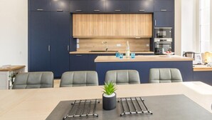 Cozinha moderna com armários escuros, bancada de madeira e ilha central com assentos.