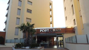 A hotel entrance with a sign reading 'PORT GRAN' and a landscaped area with plants. - Tranquil apartment, pets welcome - 4 guests (Roses)