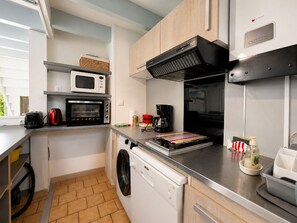 Eine kompakte Küche mit Mikrowelle, Backofen, Kaffeemaschine und Geschirrspüler.