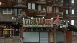 Un edificio con un letrero que dice 'LIBRAIRIE DESINTREUX' y una puerta con persiana cerrada.