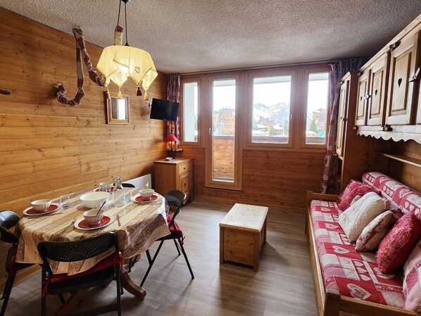 A wooden interior with a dining table set, a sofa, and a TV. - Cozy triplex apartment - 4 guests (32m²) (Avoriaz)