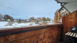 Un balcón de madera con vista a un paisaje nevado y edificios.