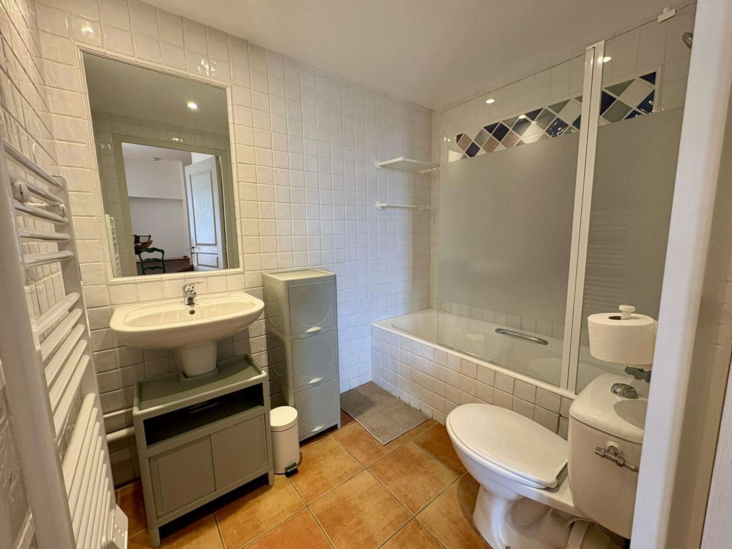 Een badkamer met een wastafel, spiegel, toilet en douche.