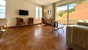 Un salón espacioso con un gran ventanal, un televisor de pantalla plana y una zona de comedor con mesa y sillas.