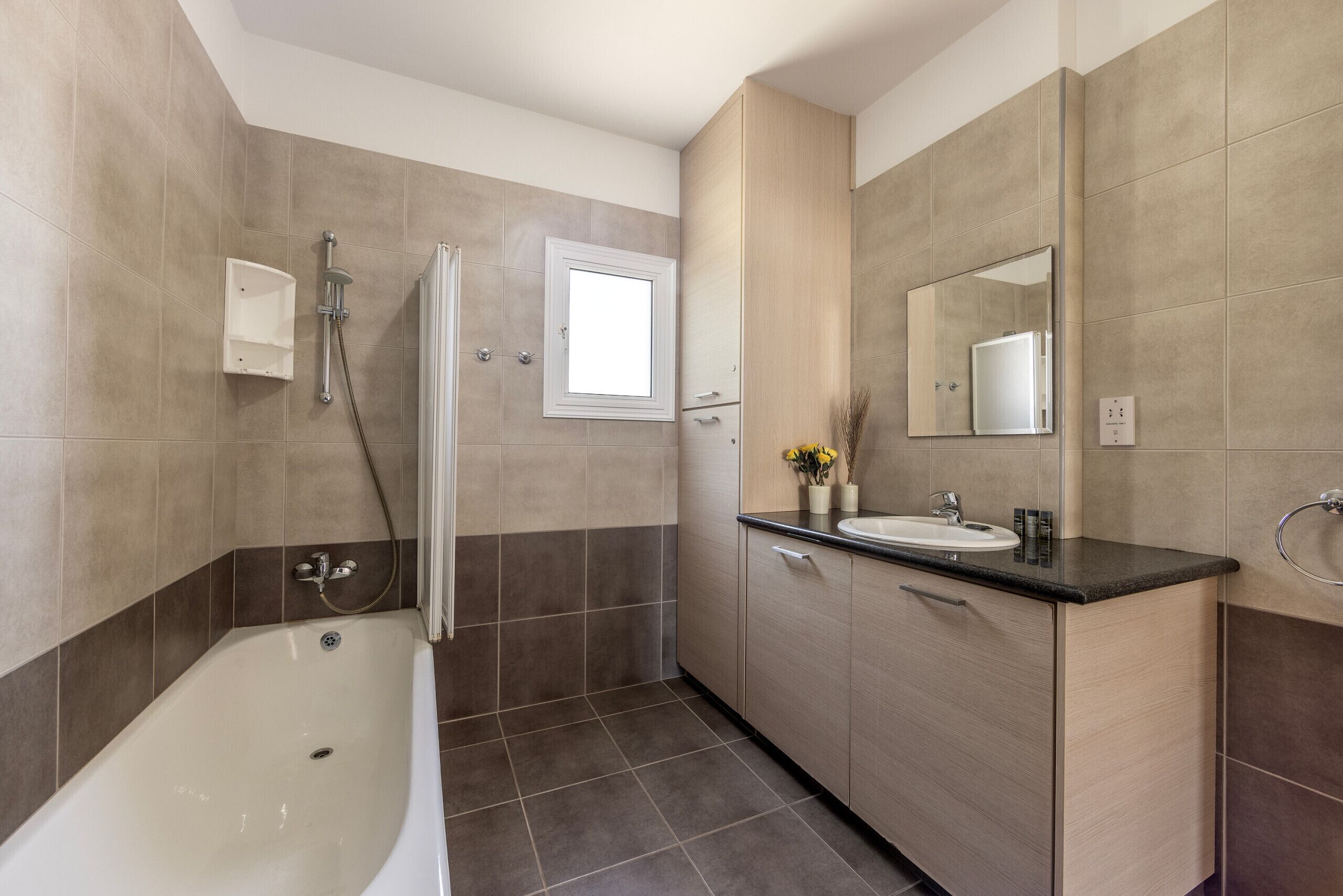 A modern bathroom with a bathtub, a shower, a sink, and a mirror.