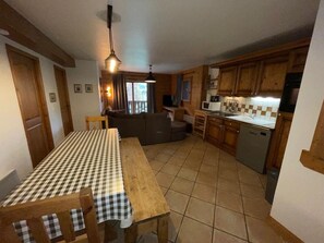 A compact kitchen with a dining table, wooden cabinets, and a built-in oven. - Spacious apartment with parking - 8 guests (Les Carroz d'Arâches)
