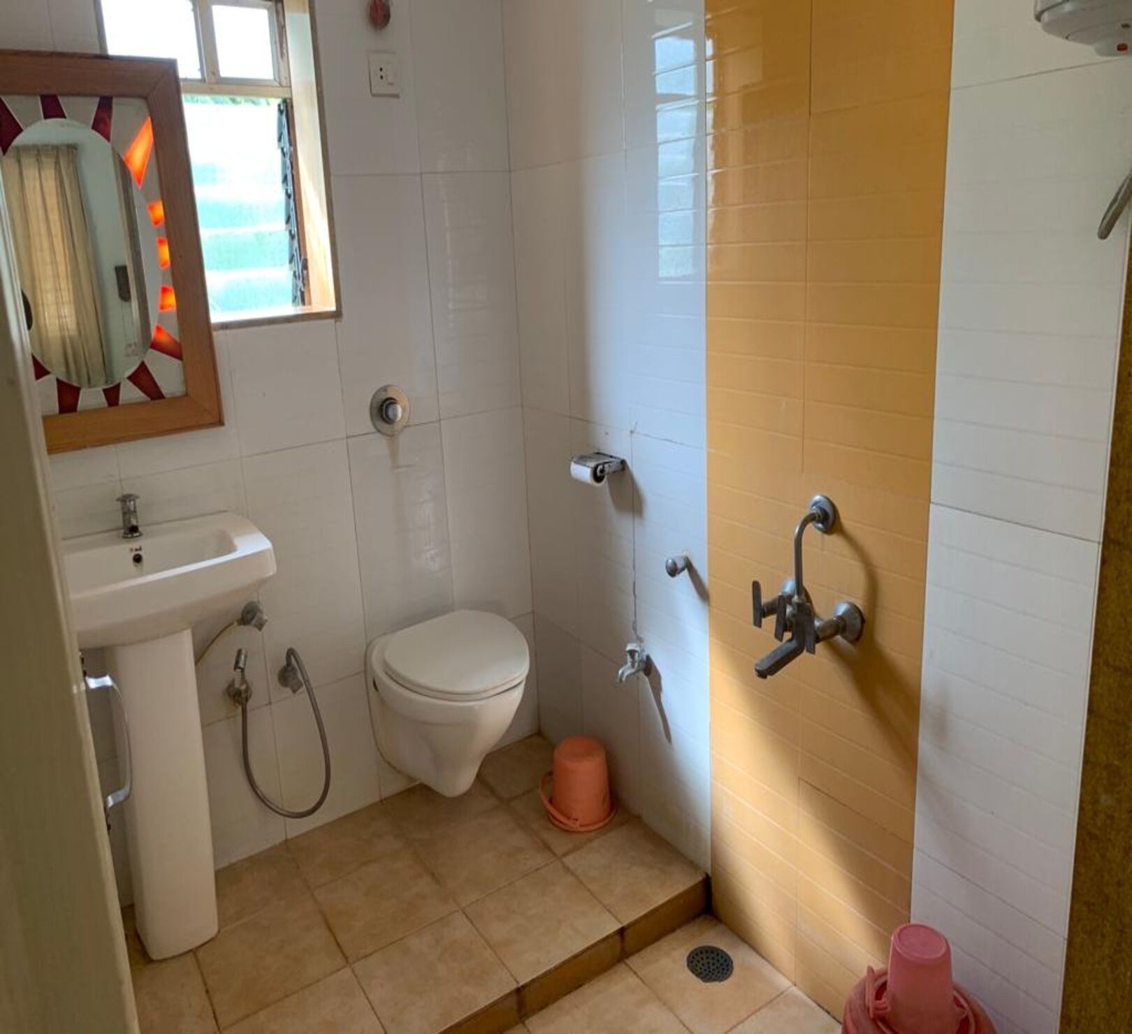 A bathroom with a toilet, sink, shower, and a mirror.