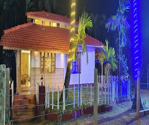 Una casa amb teulada de rajola, un porxo i un pati tancat amb palmeres.