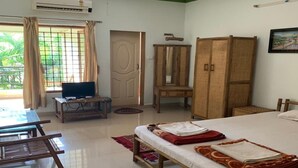 Habitación de hotel con cama, escritorio, silla, armario y televisor.