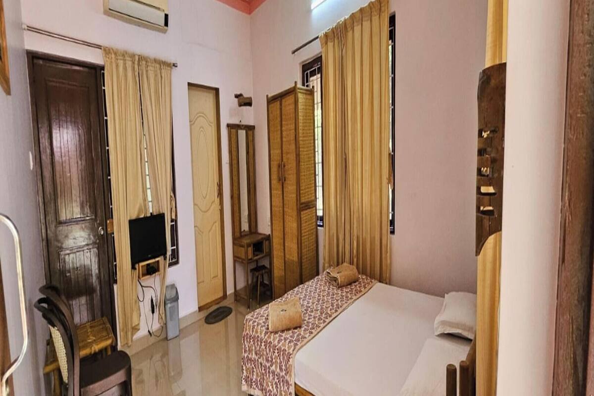 Una habitación de hotel con cama, escritorio, silla, armario y espejo.