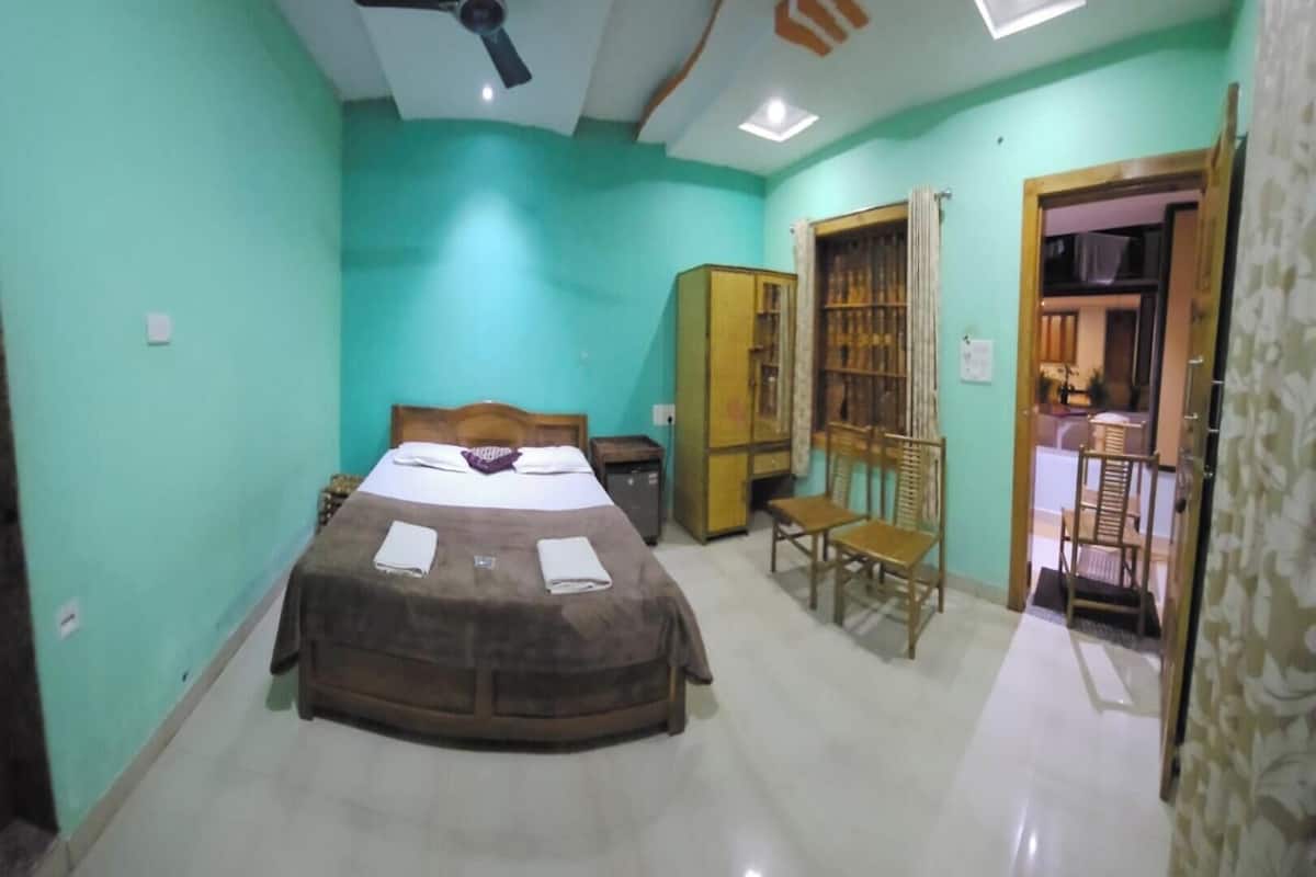 Un dormitorio con cama, ventilador de techo, armario y una silla.