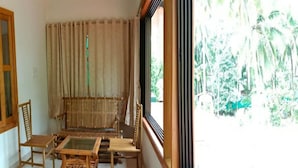 Una habitación con un ventanal amplio, un sofá, dos sillas y una mesita.