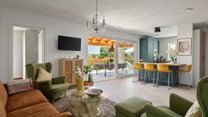 A modern living room with a sofa, chairs, a glass coffee table, a TV, and a dining area with a table and chairs. - Villa Norvegese by Villas Guide (Novigrad)