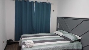Een enkel bed met een gestreept dekbedovertrek, een kussen en een opgevouwen handdoek erop.