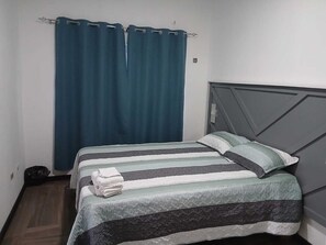 A single bed with a striped bedspread, a pillow, and a folded towel on the bed.