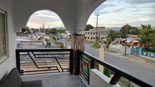 Ein Balkon mit einer Couch, Blick auf eine Straße und ein Gebäude in der Ferne.