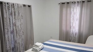 Ein Hotelzimmer mit Bett, Vorhängen, einer Klimaanlage und Holzboden.