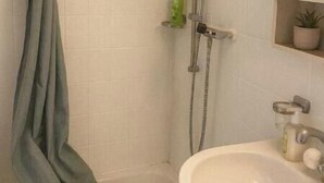 A shower with a curtain, a sink, and a mirror.